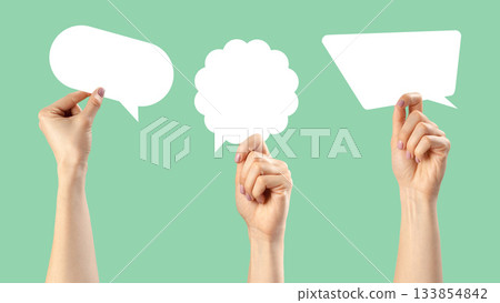 Creative hands holding empty speech bubbles on a light green background for communication ideas 133854842