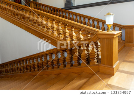 Warm wooden balusters form elegant repeating pattern along staircase in soft daylight. Smooth surfaces and crafted details create refined atmosphere with gentle shadows 133854997