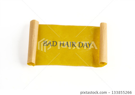 A yellow parchment scroll with rolled ends displays the phrase Bad Hair Day. The scroll rests on a plain white background, emphasizing the text and textured paper 133855266