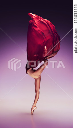 Ballet dancer stretching upward wrapped in red fabric arc on purple gradient 133855333