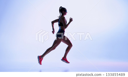 Female runner sprinting through vibrant colored light with futuristic mood 133855489