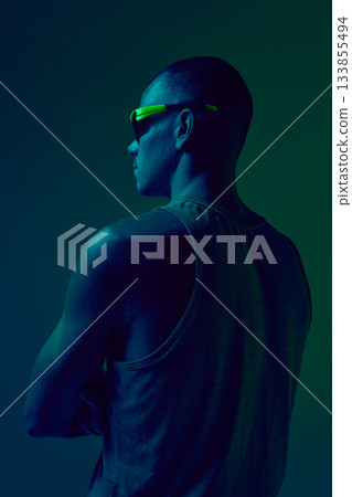 Athlete viewed from behind in neon gradient light standing in strong pose. 133855494