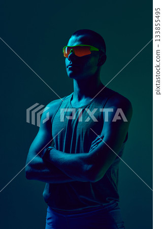 Athlete in neon lighting standing with crossed arms in confident pose 133855495