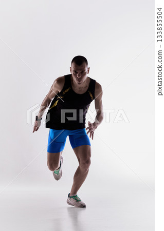 Runner accelerating forward from low leaning stance Runner accelerating forward from low leaning stance 133855504
