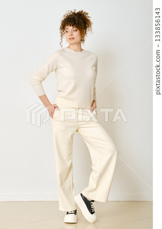 Stylish woman posing in light outfit against white background in a minimalist setting 133856143