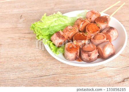 pork sausage roll up bacon stabbing plant stick dressing spicy barbecue sauce arranging with vegetable on plate pork sausage roll up bacon stabbing plant stick dressing spicy barbecue sauce arranging with vegetable on plate 133856285
