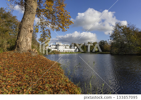 Autumn view of Soestdijk Palace reflecting in the peaceful waters of the pond in Baarn, Netherlands, surrounded by colorful foliage Autumn view of Soestdijk Palace reflecting in the peaceful waters of the pond in Baarn, Netherlands, surrounded by colorful foliage 133857095