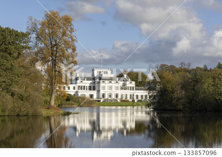 Beautiful Soestdijk Palace reflects in calm water surrounded by trees in Baarn, Netherlands during a clear day Beautiful Soestdijk Palace reflects in calm water surrounded by trees in Baarn, Netherlands during a clear day 133857096