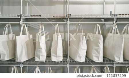 White cotton shopper bags neatly arranged on metal shelves 133857299