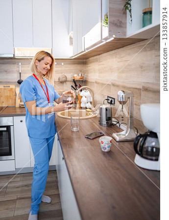 Smiling nurse preparing coffee in the kitchen during a break 133857914