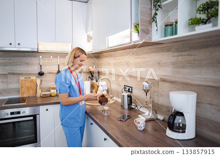 Nurse preparing instant coffee in her kitchen during a break 133857915