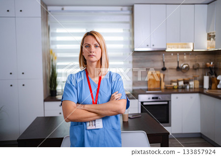 Serious doctor standing in kitchen with arms crossed 133857924