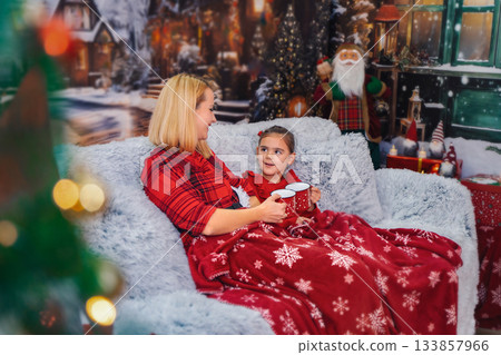 Mother and daughter enjoying hot chocolate during Christmas holiday 133857966