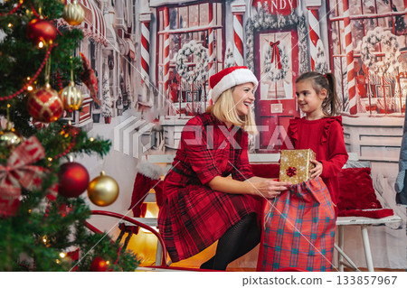 Mother giving daughter a Christmas gift during holiday celebration 133857967