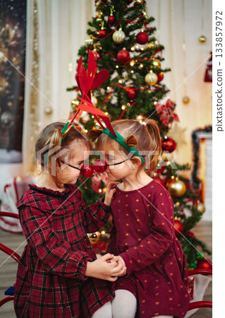 Two young sisters playing Christmas reindeer with red noses Two young sisters playing Christmas reindeer with red noses 133857972
