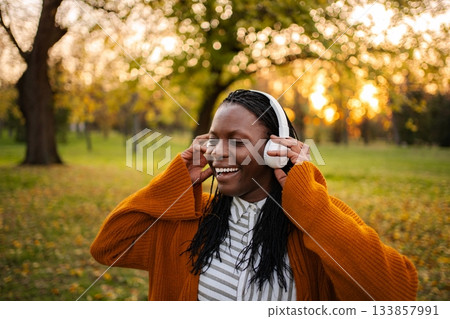 Happy young woman enjoying outdoor music in autumn park 133857991
