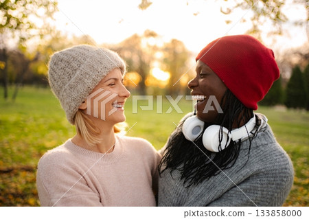 Diverse women friends laughing together outdoors during autumn Diverse women friends laughing together outdoors during autumn 133858000