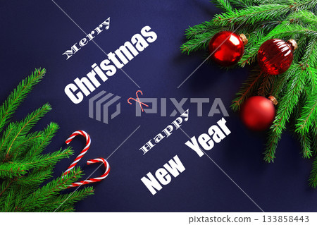 Merry Christmas Happy New Year text between fir branches, red baubles, and candy canes on a dark blue background. High quality photo Merry Christmas Happy New Year text between fir branches, red baubles, and candy canes on a dark blue background. High quality photo 133858443