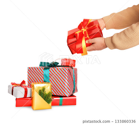 Hands placing a red and yellow wrapped gift box onto a large colorful stack of holiday presents, isolated on white background. High quality photo Hands placing a red and yellow wrapped gift box onto a large colorful stack of holiday presents, isolated on white background. High quality photo 133860336