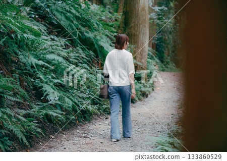 A woman walking through a cedar forest on a pilgrimage 133860529
