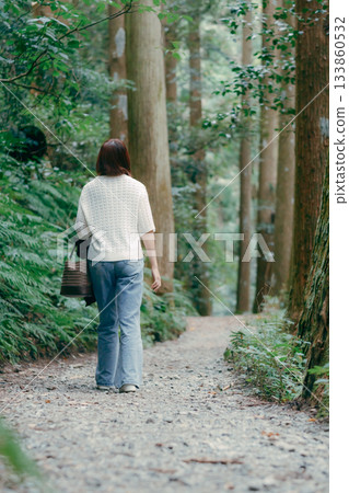 A woman walking through a cedar forest on a pilgrimage 133860532