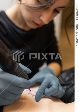 tattoo artist working on a woman chest design in a studio, showing the process of professional tattooing, precision, sterile gloves and cosmetic procedure atmosphere. tattoo artist working on a woman chest design in a studio, showing the process of professional tattooing, precision, sterile gloves and cosmetic procedure atmosphere. 133860682