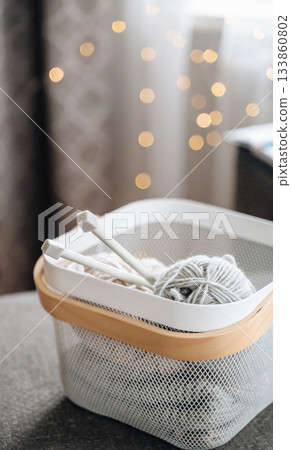 Cozy basket with yarn and knitting needles, perfect for knitting hobby and creative projects. Cozy basket with yarn and knitting needles, perfect for knitting hobby and creative projects. 133860802
