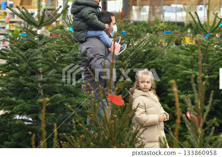 Father and children choose a Christmas tree at a forestry. Father and children choose a Christmas tree at a forestry. 133860958