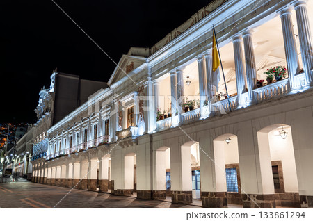 Illuminated Carondelet Palace stands on Independence Square in Quito, Ecuador. Historic presidential seat features white colonial architecture with columns under night sky 133861294