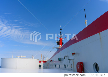 在晴朗的藍天下,從紅白相間的渡輪甲板上可以看到船體和桅杆。 在晴朗的藍天下,從紅白相間的渡輪甲板上可以看到船體和桅杆。 133861314