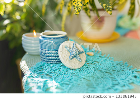 Blue ceramic jar with starfish lid on hand-knitted blue cotton scarf with seascape of fish 133861943
