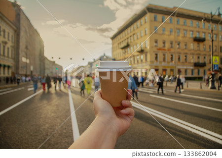 Brown paper cup of drink in women's hand on Nevsky Prospekt in center of St. Petersburg, Russia 133862004