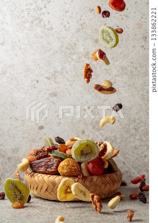 Mix of dried fruits and nuts in motion on a gray background. Mix of dried fruits and nuts in motion on a gray background. 133862221