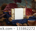 Soap bar with blank label on blue cloth near autumn dried leaves, twigs and acorns, mockup 133862272