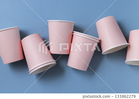 Disposable light pink paper cups on light blue in a line topview, mockup. Single-use containers 133862279