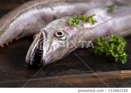 Fresh European hake fish on wooden board with parsley, Raw uncooked Merluccius merluccius close-up 133862280