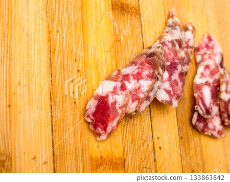 Sausage on a wooden board. 133863842