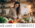 Vegan cooking prepares fresh vegetables in a kitchen setting. 133864151