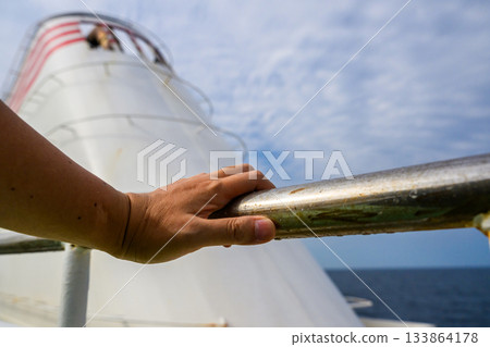 Hands holding the railing and a boat Hands holding the railing and a boat 133864178