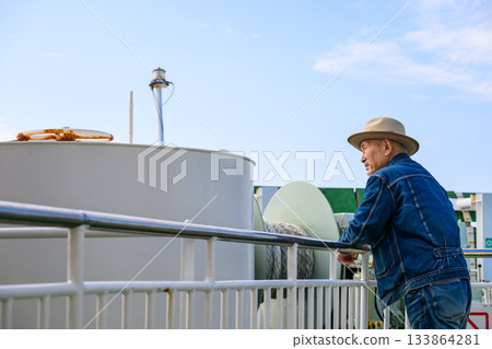 一位戴著牛仔帽的老人站在「沖繩號」渡輪的甲板上眺望大海。 一位戴著牛仔帽的老人站在「沖繩號」渡輪的甲板上眺望大海。 133864281