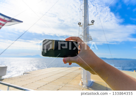 在渡輪甲板上用智慧型手機查看大海和天空 133864355