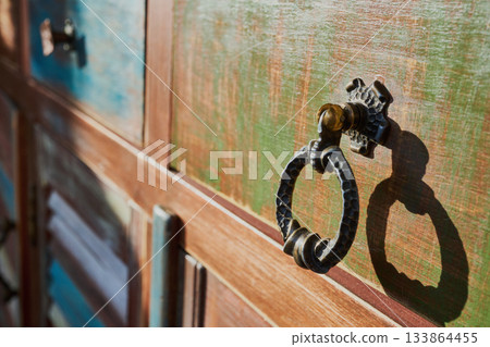 Vintage wooden door featuring antique metal ring knocker with shadow 133864455
