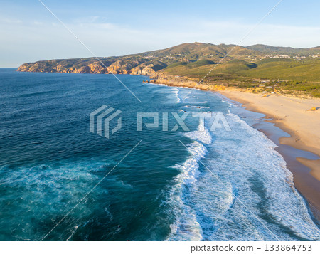 Guincho Beach, Green Mountains and Cliffs in Evening. Aerial View. Atlantic Ocean, Portugal Guincho Beach, Green Mountains and Cliffs in Evening. Aerial View. Atlantic Ocean, Portugal 133864753