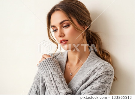 Beautiful thoughtful woman in a warm gray cable knit sweater with elegant pearl necklace Beautiful thoughtful woman in a warm gray cable knit sweater with elegant pearl necklace 133865513