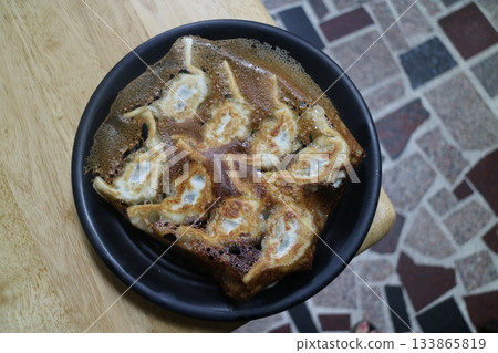 Close-up of pan-fried dumplings on a black plate Close-up of pan-fried dumplings on a black plate 133865819