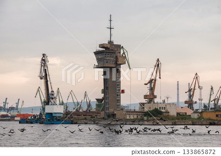 A scenic coastal view of an industrial Varna port featuring cranes and a watchtower 133865872