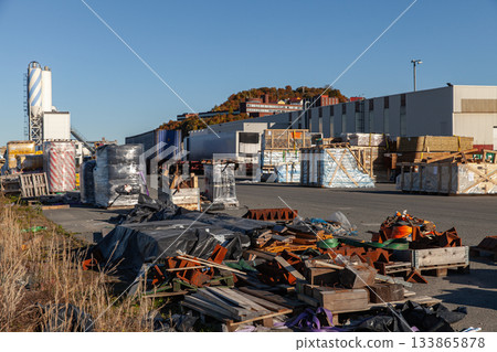 A busy outdoor industrial yard filled with pallets, scrap metal and wrapped bundles A busy outdoor industrial yard filled with pallets, scrap metal and wrapped bundles 133865878