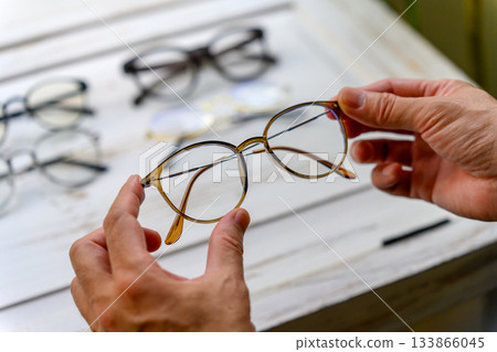 A man picking up a pair of round glasses A man picking up a pair of round glasses 133866045