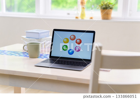 明亮的窗戶旁，桌子上放著一台筆記型電腦，螢幕上顯示著色彩繽紛的餅圖。 133866051