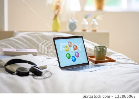 Relaxing in bed with a laptop and headphones Relaxing in bed with a laptop and headphones 133866062